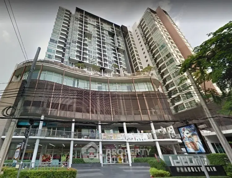 Modern high-rise condominium with retail shops at base, ideal urban living.