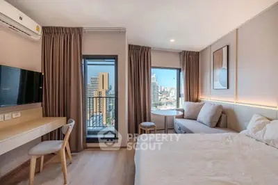 Modern bedroom with city view, featuring cozy seating area and stylish decor.