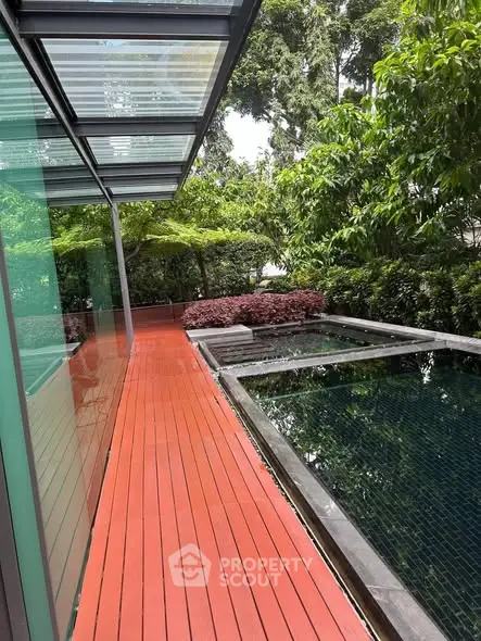 Luxurious modern poolside with lush greenery and sleek glass architecture.