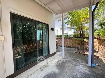 Charming patio with sliding glass doors and lush greenery, perfect for outdoor relaxation.
