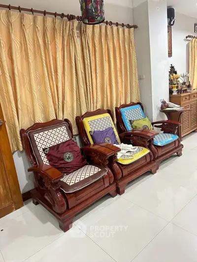 Charming living room with elegant wooden chairs and cozy cushions, perfect for relaxation and style.
