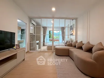Modern living room with stylish sofa and glass partition leading to bedroom