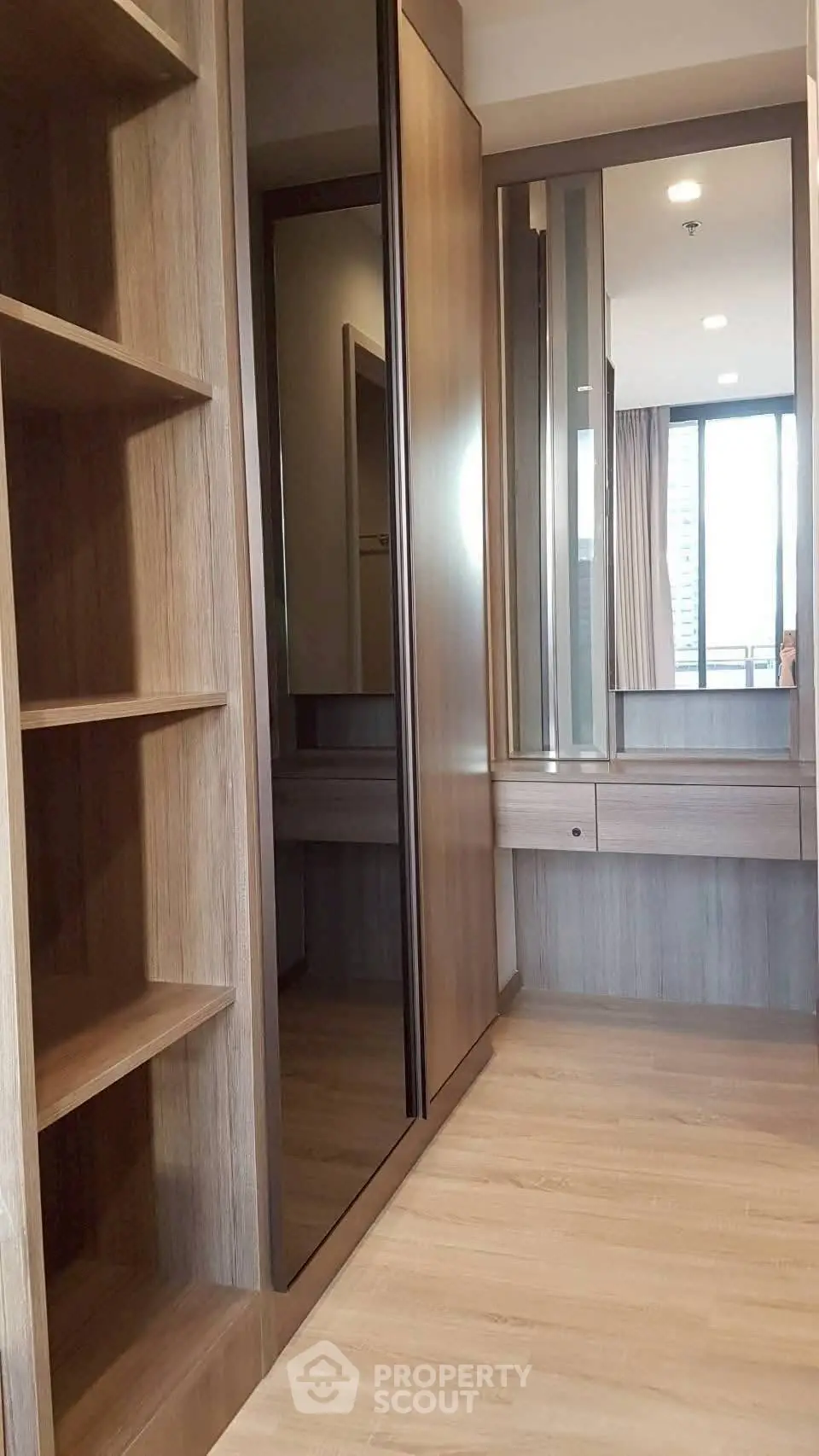 Spacious walk-in closet with modern wooden shelving and mirrored doors