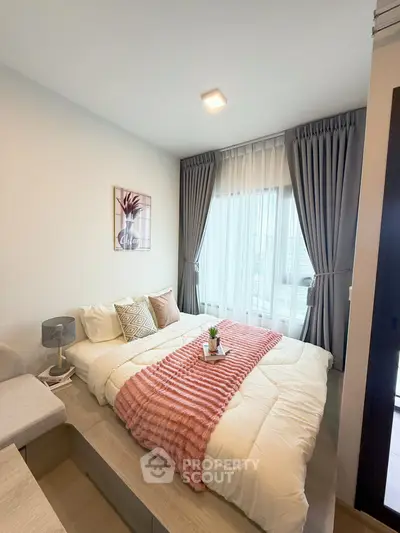 Cozy bedroom with modern decor, featuring a large window with elegant curtains and a comfortable bed.