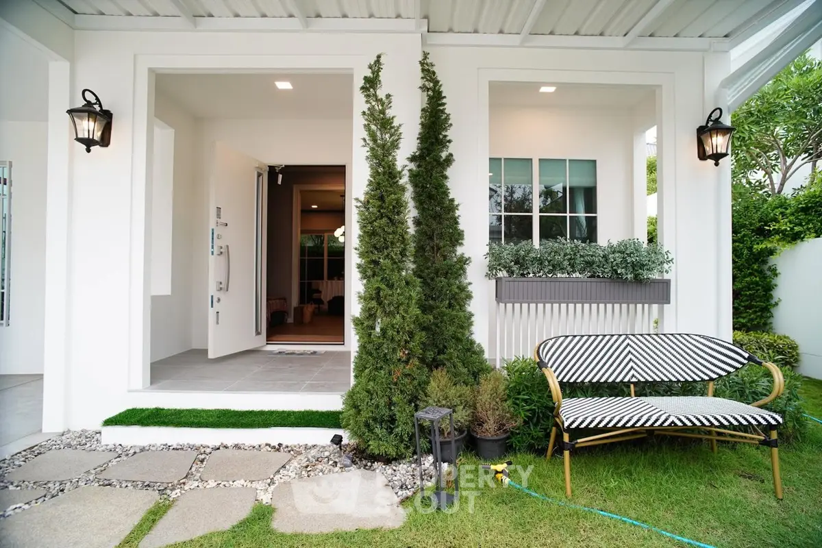 Charming modern home exterior with lush garden and stylish outdoor seating area.