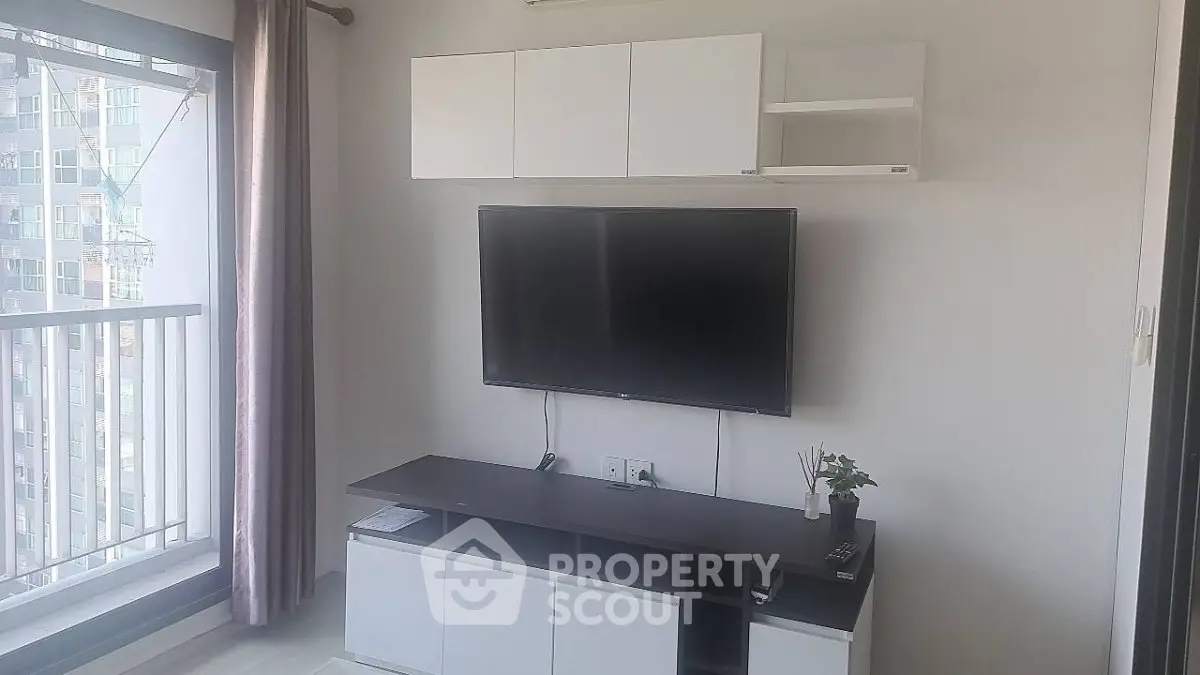 Modern living room with wall-mounted TV and sleek furniture in a bright apartment.