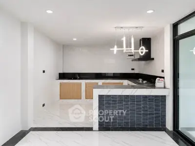 Modern kitchen with sleek design, featuring marble flooring and contemporary lighting in a stylish open layout.