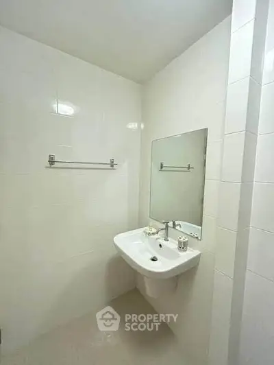 Modern minimalist bathroom with sleek white tiles and a wall-mounted sink.