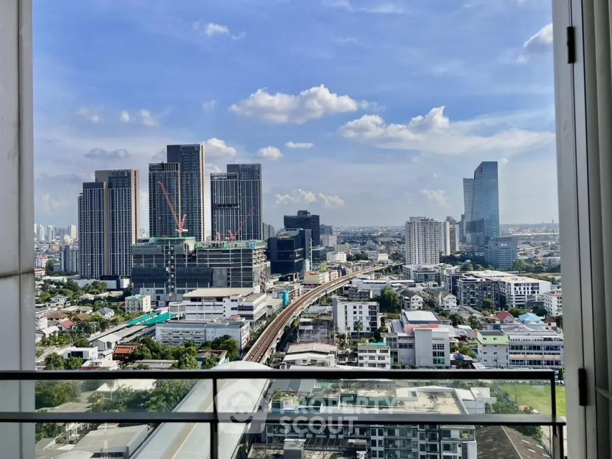 Stunning cityscape view from a high-rise balcony with modern skyscrapers and clear blue sky.
