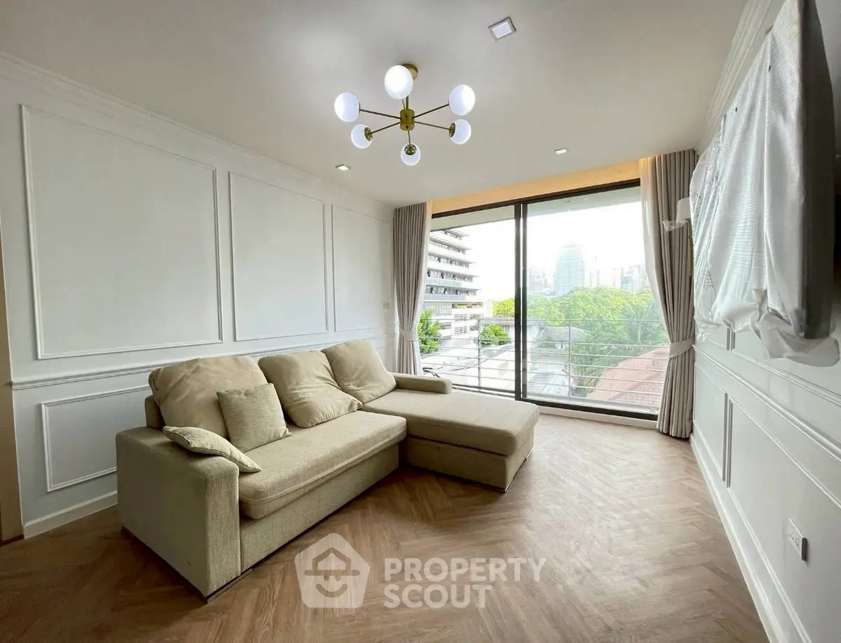 Spacious living room with modern decor and large window offering a stunning city view.
