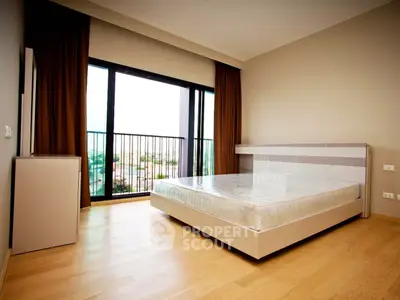 Spacious modern bedroom with large window and balcony view, featuring minimalist design and natural light.