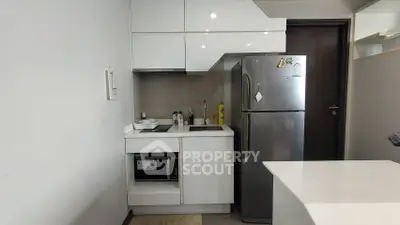Modern compact kitchen with sleek white cabinets and stainless steel appliances