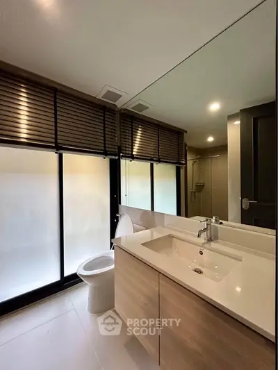 Modern bathroom with sleek design, featuring large mirror and contemporary fixtures.