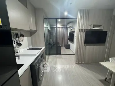 Modern apartment interior with sleek kitchen and living area, featuring built-in appliances and stylish decor.
