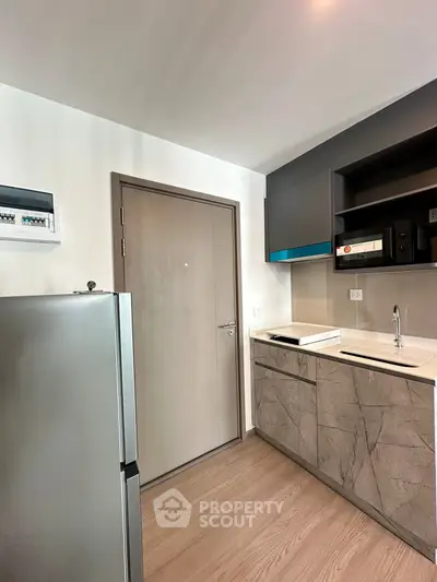 Modern kitchen with sleek cabinetry and stainless steel fridge in contemporary apartment.