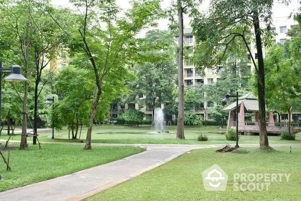 Serene garden oasis with lush greenery and tranquil fountain, nestled within a modern residential complex, offering a peaceful retreat.