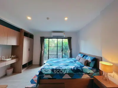 Spacious bedroom with modern decor and large window overlooking greenery.