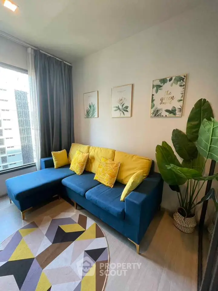 Stylish living room with modern decor, vibrant blue sofa, and large window view in urban apartment.
