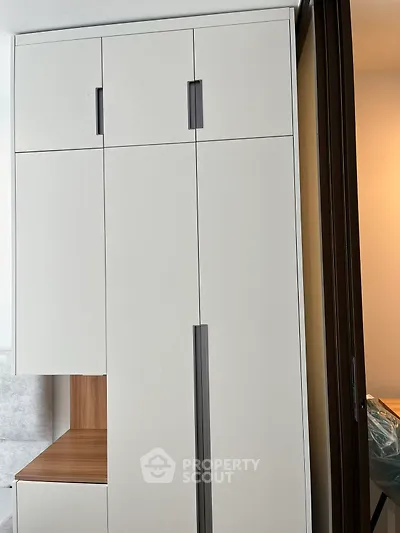 Modern white wardrobe with sleek handles in a stylish bedroom setting.