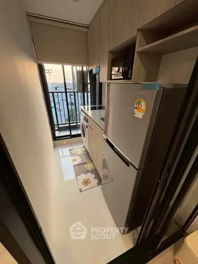 Compact kitchen with modern appliances and balcony view in urban apartment