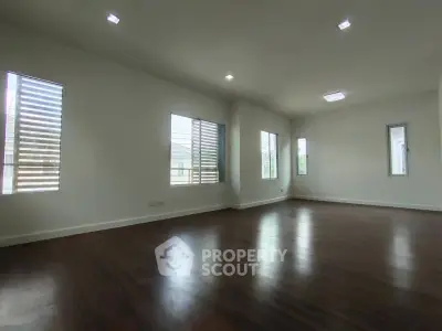 Spacious empty living room with wooden floors and large windows