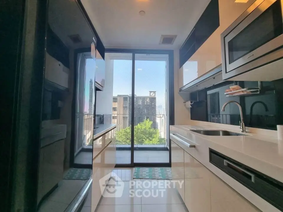 Modern kitchen with sleek appliances and stunning city view through large glass doors.