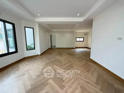 Spacious modern living room with elegant wooden flooring and ample natural light.