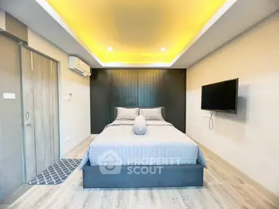 Modern bedroom with ambient lighting and sleek design, featuring a comfortable bed and wall-mounted TV.