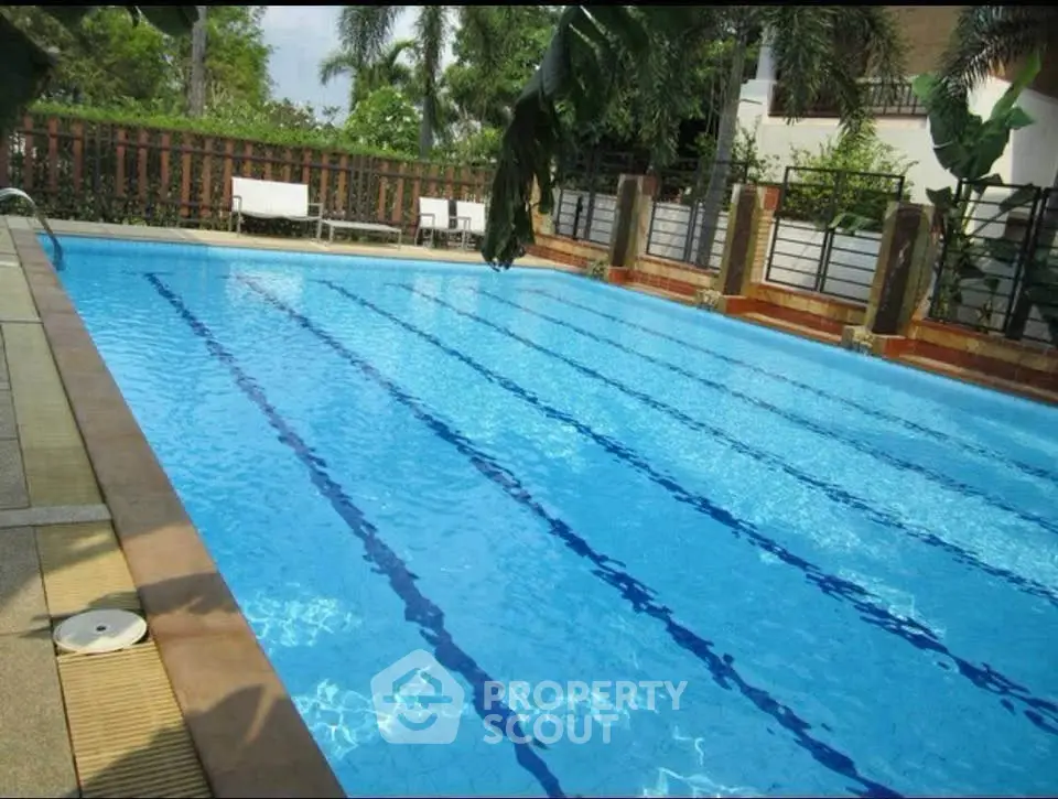 Luxurious outdoor swimming pool with clear blue water and lush greenery surroundings.