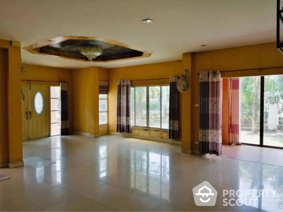 Expansive and sunlit living room with glossy tiled floors, large windows, and a unique ceiling design, offering a perfect canvas for personalized decor.