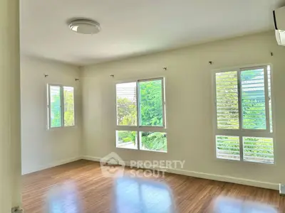 Bright and airy room with large windows and wooden flooring, perfect for a cozy living space.