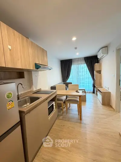 Modern open-layout kitchen and living room with stylish wooden furniture and large window view.