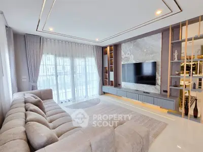 Luxurious modern living room with plush sofa and large TV, featuring elegant decor and ample natural light.
