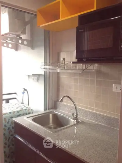 Compact kitchen with granite countertop and microwave in modern apartment