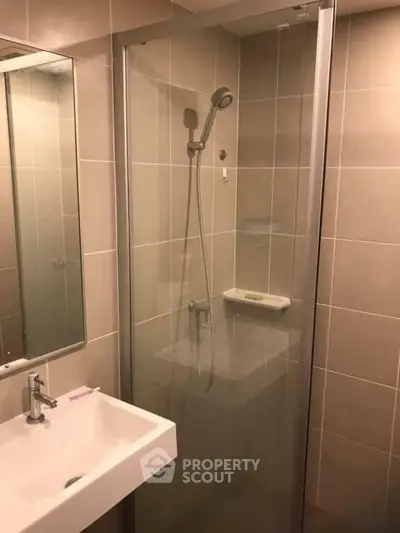 Modern bathroom with glass shower enclosure and sleek sink design.