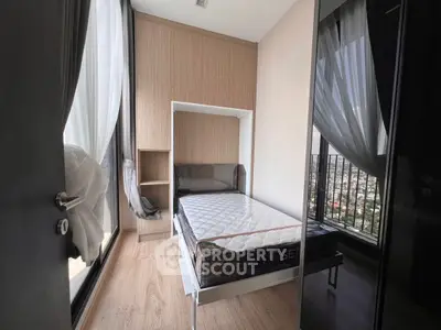 Modern bedroom with large windows and city view, featuring sleek design and natural light.