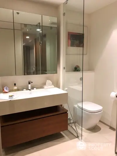 Modern bathroom with glass shower and sleek vanity in luxury apartment.