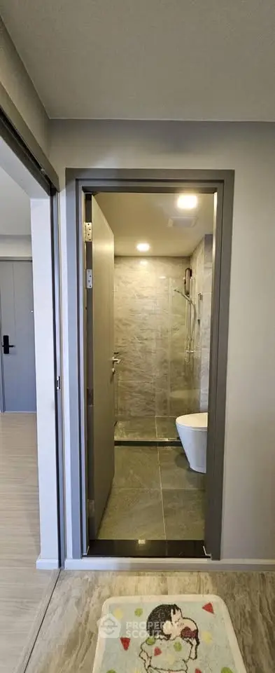 Modern bathroom with sleek design and glass shower enclosure in a contemporary apartment.