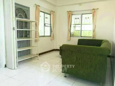 Cozy living room with green sofa and natural light, perfect for relaxation.