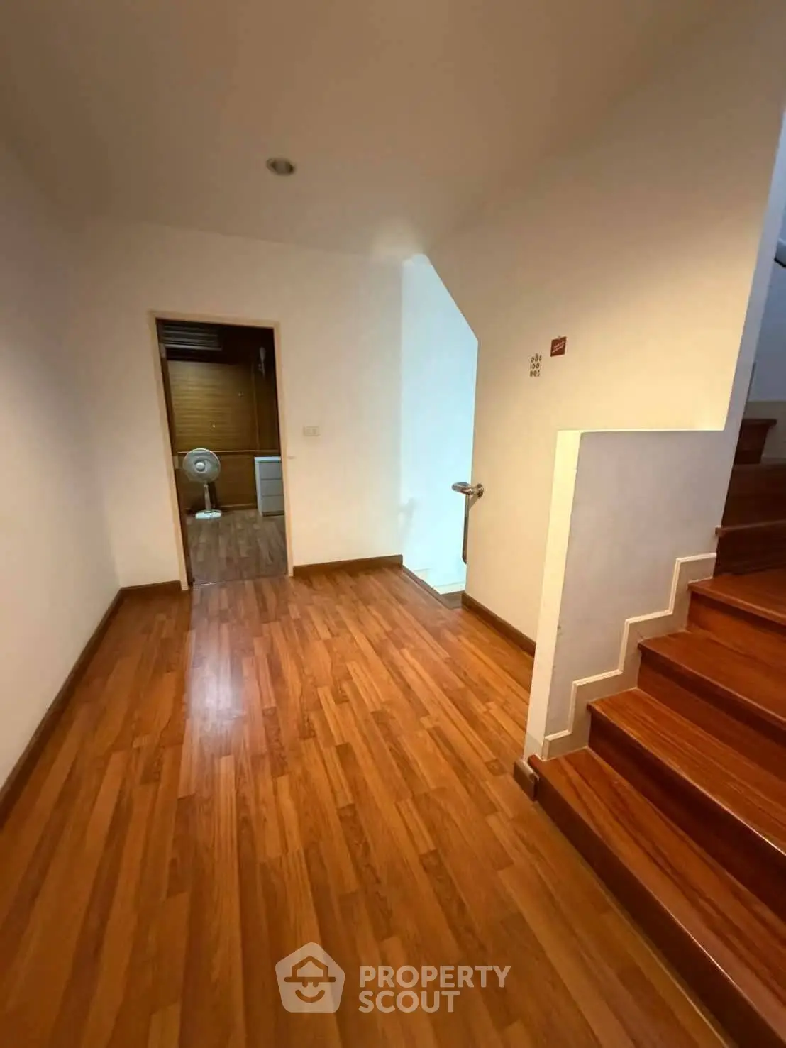 Spacious hallway with wooden flooring and staircase in modern home