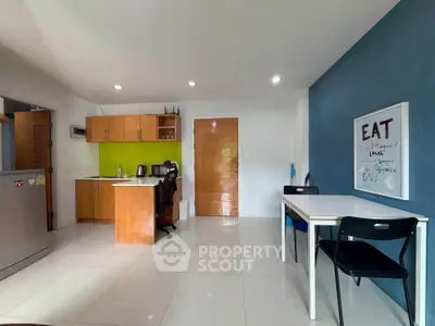 Modern kitchen with dining area, featuring sleek cabinets and vibrant accent wall.