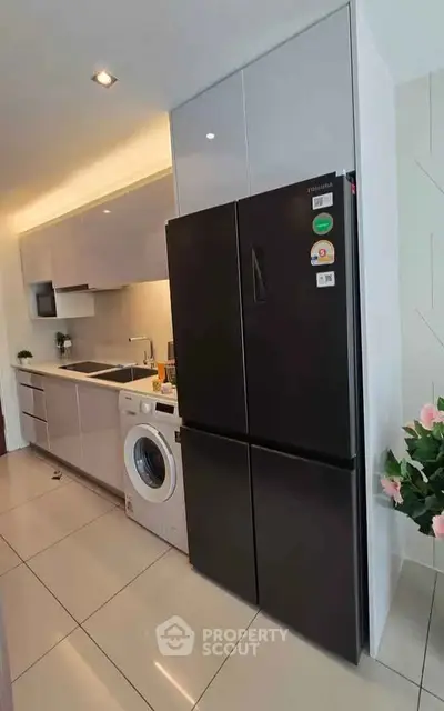 Modern kitchen with sleek appliances and washing machine in stylish apartment.