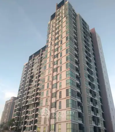 Modern high-rise residential building with glass balconies and sleek design.