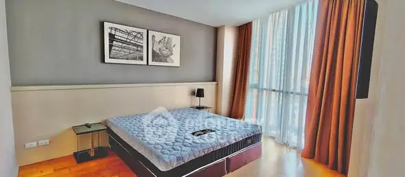Spacious bedroom with modern decor and large window in a luxury apartment.