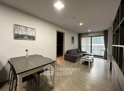 Modern living room with sleek furniture and city view from balcony.