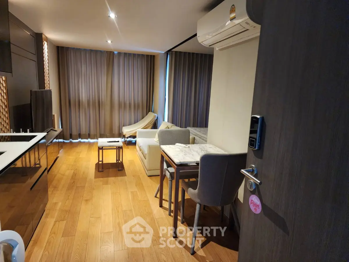 Modern living room with wooden flooring, stylish furniture, and air conditioning.