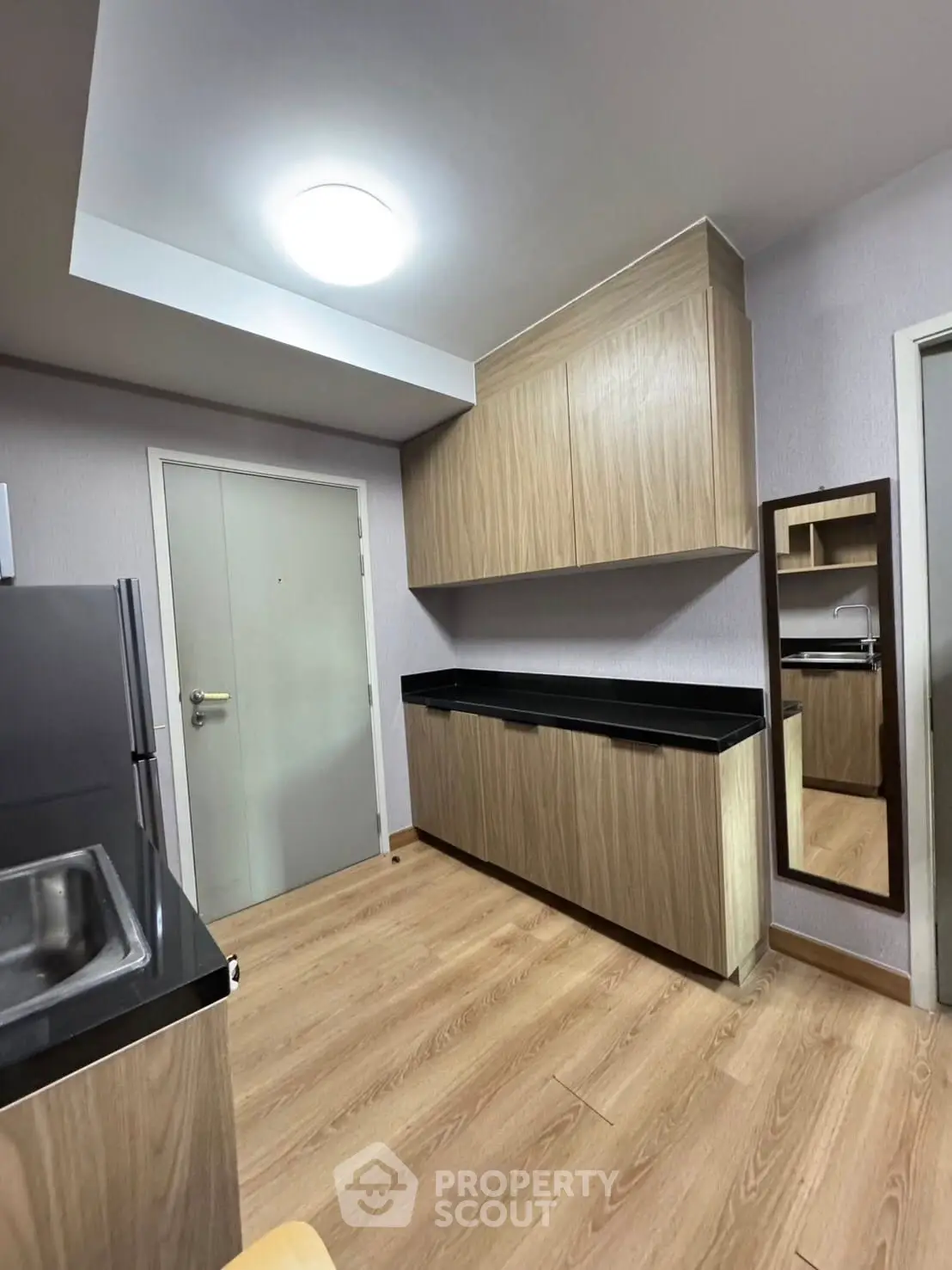 Modern kitchen with sleek wooden cabinets and black countertops in a stylish apartment.