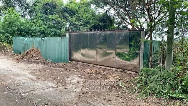 Spacious plot with secure metal gate and lush greenery