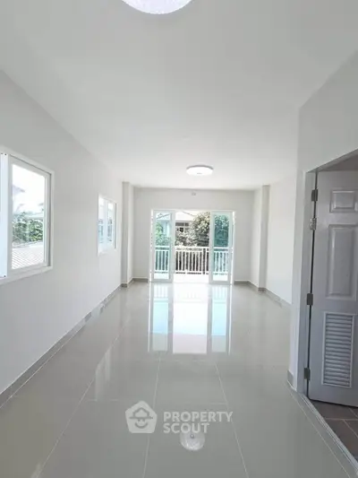 Spacious and bright living room with glossy tiled floors and large windows offering natural light.