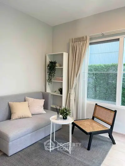 Charming living room with modern decor, featuring a cozy sofa, stylish chair, and natural light from large window.